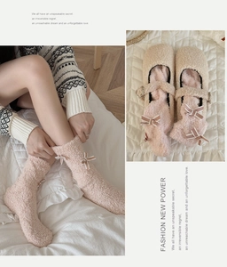 Detailansicht der rosa Korallenvlies-Socken mit Schleifen und beige Hausschuhe