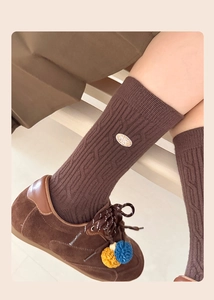 Dettaglio macro di calze in maglia a trecce marrone con scarpe scamosciate marroni retrò