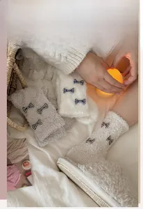 Detailed view of plush coral fleece socks set featuring elegant black and white plaid bows