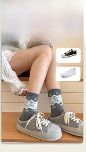 Detail view of grey winter crew socks with white snowflake and mountain patterns
