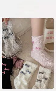 Detail of coral fleece socks featuring elastic cuffs and delicate plaid bow decoration