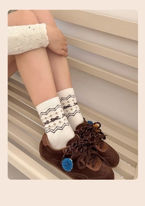 Dettaglio di calze in maglia retrò Fair Isle con motivi marroni e sneakers soffici