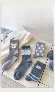 Detail view of four pairs of grey wool-like socks featuring cute cartoon dog and stripe patterns