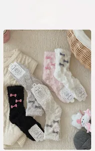 Close-up of coral fleece socks with bow detail in warm cozy home setting decor
