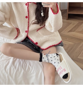 Detailed close-up of fuzzy coral fleece socks with black polka dots and cute bow detail