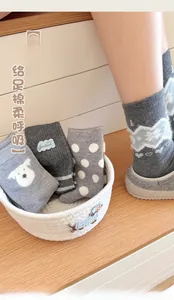 Close-up of gray cashmere-style socks with cute dots, stripes, and bear patterns in a basket