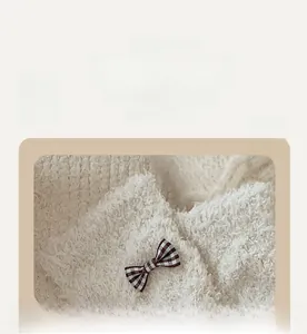 Detail of soft coral fleece socks with elastic cuff and a decorative plaid bow