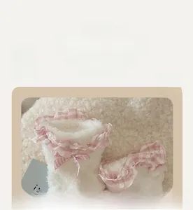 Dettaglio calzino in pile corallo bianco con pizzo a quadretti rosa e fiocco dolce