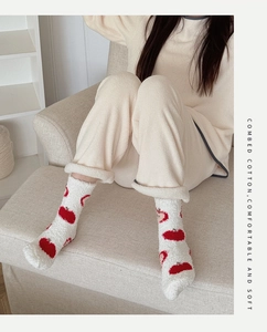Détail de chaussettes en polaire corail blanche à motif pomme rouge dans un cadre douillet