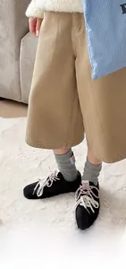 Detail view of grey ribbed wool socks with blue patch, styled with sneakers on a carpet
