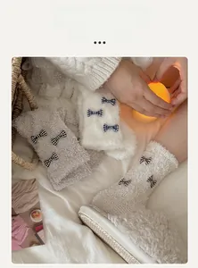Close-up of thick coral fleece winter socks featuring decorative black and white bows