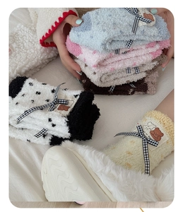 Detail of coral fleece thick socks showing checkered bow and cute bear patch decoration
