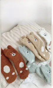Close-up of fluffy coral fleece socks with cute cartoon embroidery and soft ears