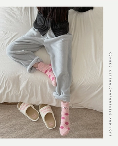Detail of pink coral fleece socks with cat embroidery and white plush slippers