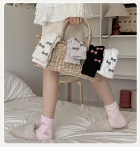 Close-up of thick coral fleece warm socks with bow decorations in a woven basket