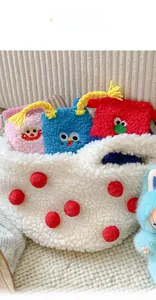 Detail view of a white fleece tote bag with colorful monster-themed plush storage pouches