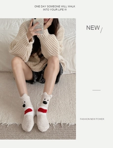 Close-up of fluffy cream coral fleece socks featuring a cute cartoon bear face design