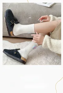 Detail of white ribbed cotton socks with pink cartoon patch and gray wool mule shoes