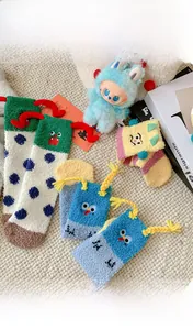 Close-up of funny thick coral fleece socks with cartoon faces and 3D braided details