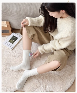 Detail of white ribbed wool socks with blue cartoon patch on a cozy home carpet