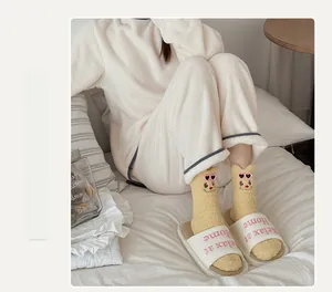 Detail of yellow coral fleece socks with bear embroidery and white home slippers