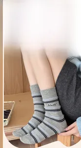 Close-up of grey and blue striped wool socks with black As You Wish embroidery lettering