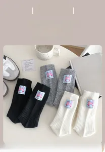 Detail of wool socks with pink cartoon patch and Sweet Life text in black, grey, and white
