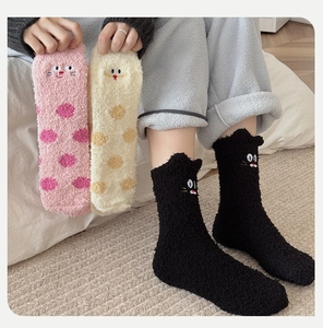 Close-up of warm coral fleece socks featuring cute cat embroidery and polka dot patterns