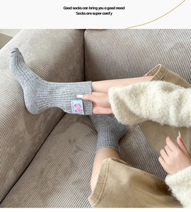 Macro detail of grey knit wool socks with sweet life cartoon patch on the ribbed cuff