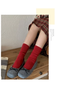 Detailed view of red waffle knit silk wool socks paired with dark grey bow loafers