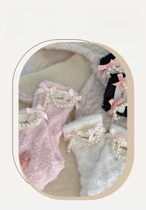 Detail of coral fleece socks with satin bows, faux pearls, and woven brand labels