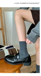 Detail of grey ribbed wool silk crew socks paired with black leather loafers