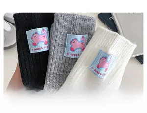Detail of wool socks featuring a pink cartoon cat patch and ribbed knit texture