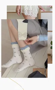 Close-up of ballet style cream socks featuring grey bow prints and ruffled edges