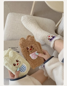Detailed close-up of thick coral fleece socks with cute cartoon bear embroidery and soft texture