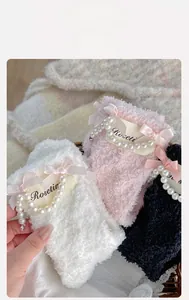 Detail of coral fleece socks with satin bows, pearls and brand labels on knit blanket