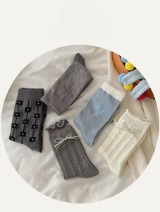 Flat lay of five pairs of grey and beige cotton socks with floral embroidery and bows