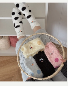 Close-up of warm coral fleece socks with cute cartoon cat embroidery and polka dot patterns