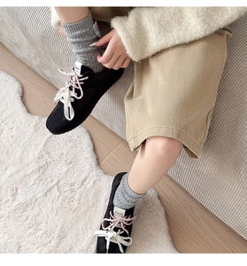 Close-up of black suede sneakers with layered pink and white laces and Smile tag