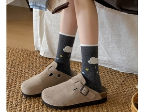 Close-up of suede clogs with dark grey cartoon star and cloud pattern knit socks