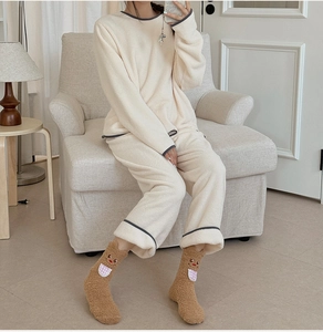 Detail of warm cream fleece lounge set with fuzzy animal pattern socks and grey piping edges