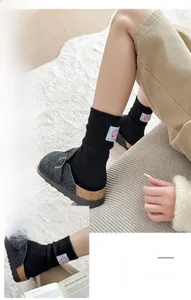 Detail view of dark grey wool slippers with metal buckles and pink label socks