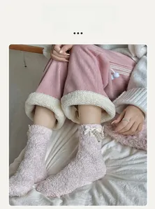 Detail of light pink coral fleece sock with white satin bow and pearl ornaments