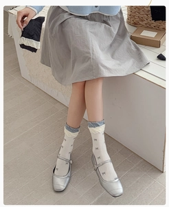 Detail of white crew socks with grey bow patterns and double ruffled cuffs with Mary Janes