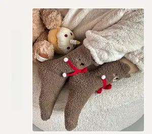 Detail of warm brown coral fleece socks with 3D teddy bear design and red ribbon accent
