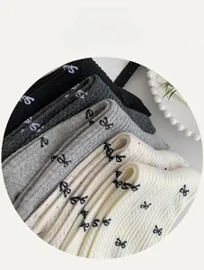 Detail of stacked mid-calf socks featuring ribbon patterns in black, grey, and white tones