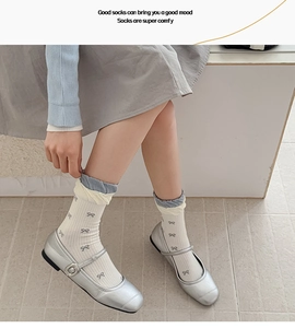 Detail of cream calf socks with bow patterns and blue ruffled edges in Mary Jane shoes