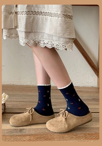 Detail of navy blue cotton socks with floral embroidery and white scalloped edge