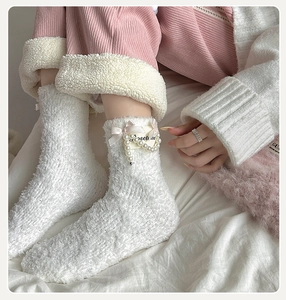 Detail of white coral fleece socks with pink silk bow and pearl beads decorations