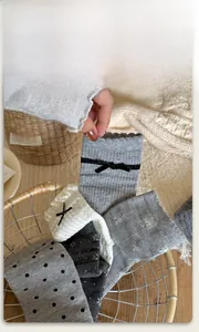 Detailed shot of grey cotton socks featuring black bows, polka dots and lace trim textures